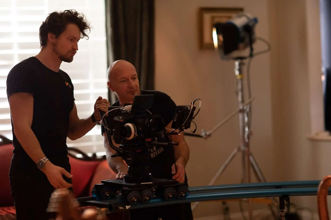 Film crew setting up equipment indoors.